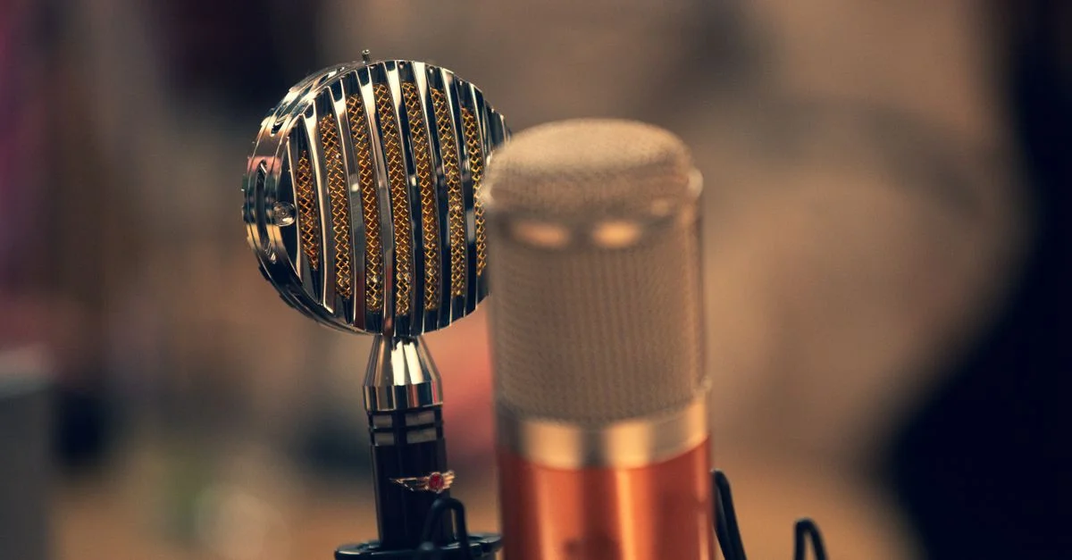 Gros plan sur un microphone vintage et un microphone moderne dans un studio d'enregistrement avec une ambiance chaleureuse.