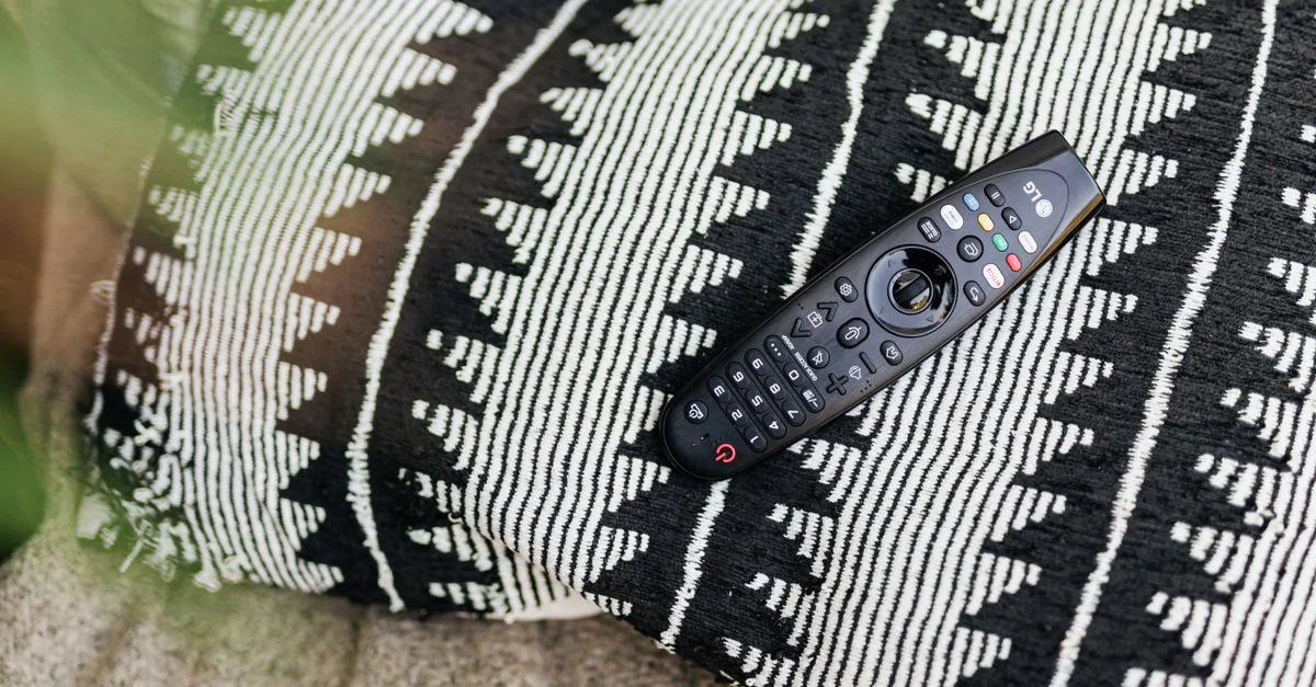 Gros plan sur une télécommande noire reposant sur un coussin décoratif à motifs.